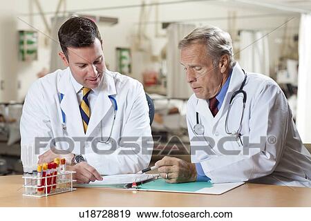 Two doctors reading medical document in hospital View Large Photo Image Stock Photo - Two doctors reading medical document in hospital. Fotosearch