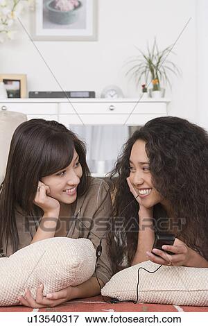 Two friends listening to mp3 player View Large Photo Image Stock Photo - Two friends listening to mp3 player. Fotosearch