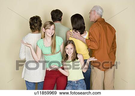 Two girls (8-9, 14-15) gesturing as rest of family is standing reversed View Large Photo Image Stock Photo - Two girls (8-9, 14-15) gesturing as rest of family is standing reversed. Fotosearch