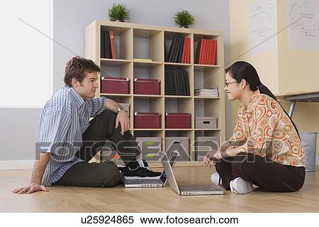 Stock Photography - Two office workers sitting on floor with their laptops. Fotosearch