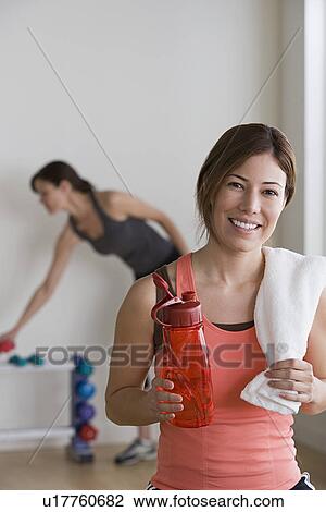 Stock Image - Two women exercising in gym. Fotosearch