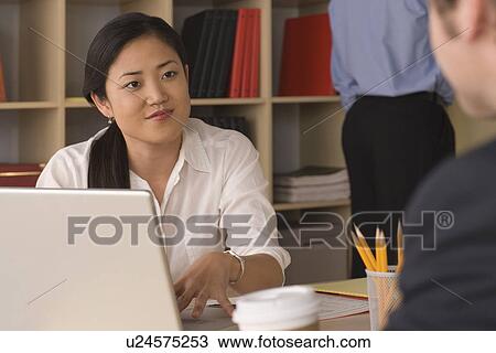 Stock Image - Two young businesspeople at meeting . Fotosearch