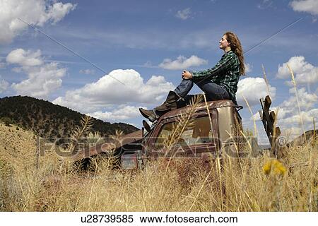 USA, Colorado, Woman resting on roof of abandoned truck in desert View Large Photo Image Stock Photography - USA, Colorado, Woman resting on roof of abandoned truck in desert. Fotosearch