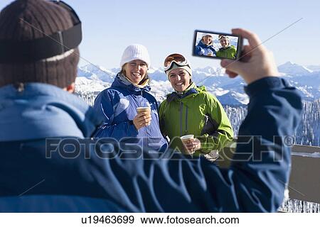 USA, Montana, Whitefish, Man photographing two women in mountain resort View Large Photo Image Stock Photo - USA, Montana, Whitefish, Man photographing two women in mountain resort. Fotosearch