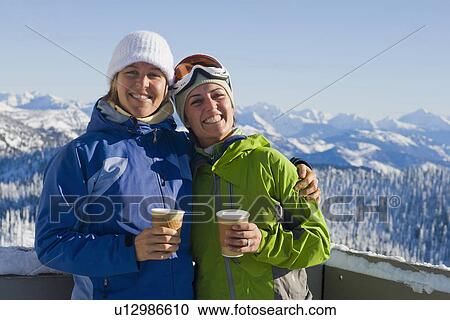 Stock Image - USA, Montana, Whitefish, Portrait of two women with mountains as backdrop. Fotosearch