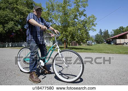 Stock Image - USA, Montana, Whitefish, Portrait of senior man on bike. Fotosearch