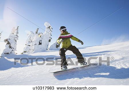 Stock Image - USA, Montana, Whitefish, Snowboarder on slope. Fotosearch