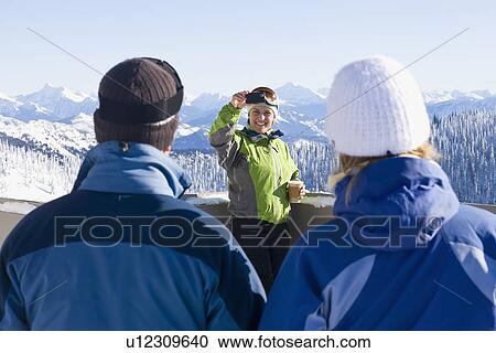 Stock Image - USA, Montana, Whitefish, Woman photographing friends in mountain resort. Fotosearch