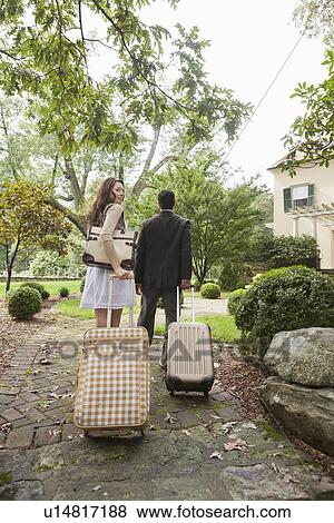 Stock Photo - USA, New Jersey, Couple walking up path with luggage. Fotosearch
