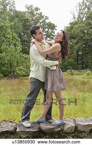 Stock Image - USA, New Jersey, Happy couple embracing on stone wall. Fotosearch