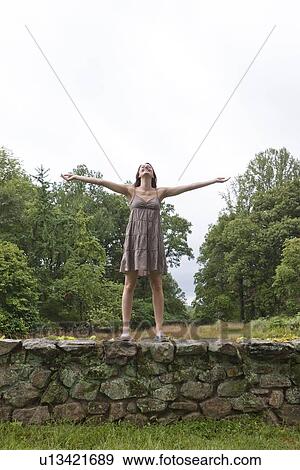 USA, New Jersey, Happy woman standing on stone wall on field View Large Photo Image Stock Photo - USA, New Jersey, Happy woman standing on stone wall on field. Fotosearch