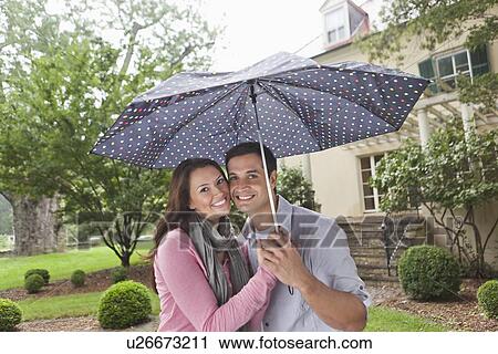Stock Image - USA, New Jersey, Portrait of couple holding umbrella. Fotosearch