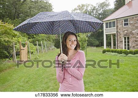 Stock Photograph - USA, New Jersey, Portrait of woman holding umbrella. Fotosearch