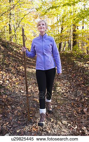 Stock Photography - USA, New Jersey, Smiling woman hiking in Autumn forest. Fotosearch