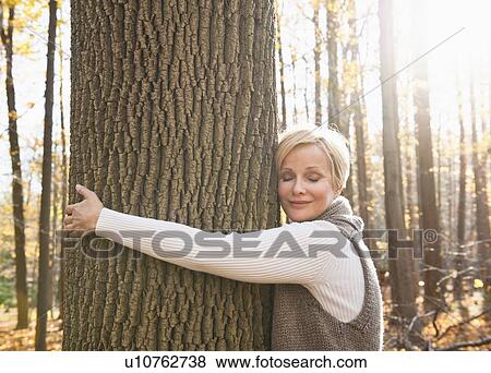 USA, New Jersey, Smiling woman hugging tree in Autumn forest View Large Photo Image Stock Photo - USA, New Jersey, Smiling woman hugging tree in Autumn forest. Fotosearch