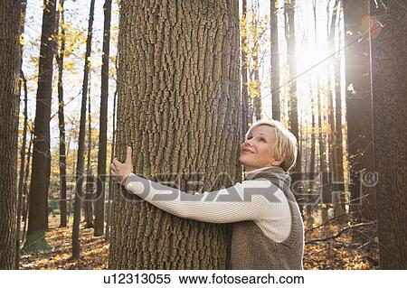 USA, New Jersey, Smiling woman hugging tree in Autumn forest View Large Photo Image Stock Photography - USA, New Jersey, Smiling woman hugging tree in Autumn forest. Fotosearch