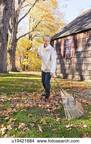 USA, New Jersey, Woman raking leaves in front of house View Large Photo Image Picture - USA, New Jersey, Woman raking leaves in front of house. Fotosearch