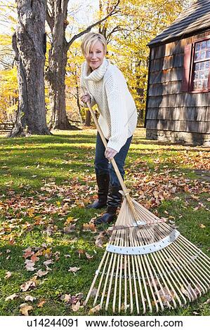 USA, New Jersey, Woman raking leaves in front of house View Large Photo Image Stock Image - USA, New Jersey, Woman raking leaves in front of house. Fotosearch