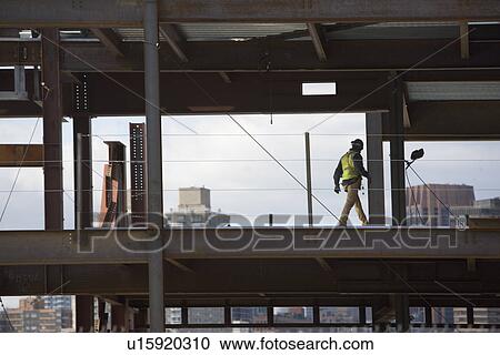 Stock Image - USA, New York City, Construction worker walking inside of unfinished structure. Fotosearch