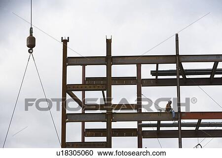 Stock Image - USA, New York City, Construction worker sitting on unfinished structure. Fotosearch