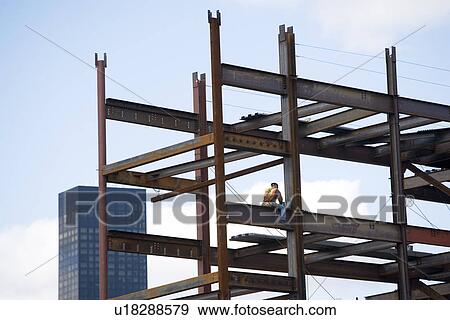 Stock Photo - USA, New York City, Construction worker sitting on unfinished structure. Fotosearch