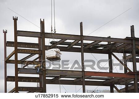 Stock Photography - USA, New York City, Construction worker sitting on unfinished structure. Fotosearch