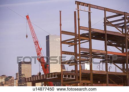 Stock Image - USA, New York City, Crane with unfinished structure and Manhattan skyline in background. Fotosearch