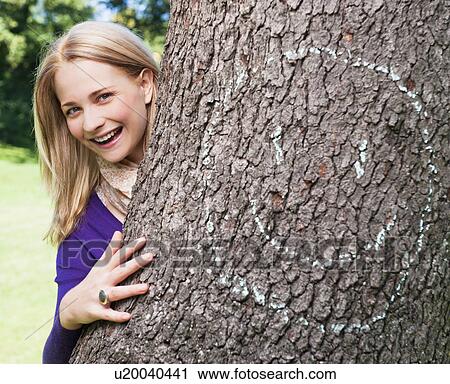 Stock Image - USA, New York, New York City, Manhattan, Central Park, Young woman embracing tree. Fotosearch
