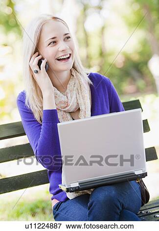 USA, New York, New York City, Manhattan, Central Park, Young woman sitting on bench with laptop and mobile phone View Large Photo Image Stock Photo - USA, New York, New York City, Manhattan, Central Park, Young woman sitting on bench with laptop and mobile phone. Fotosearch