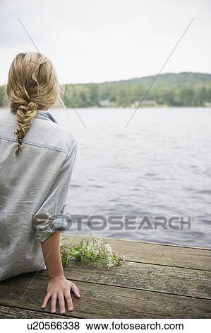 Stock Photo - USA, New York, Putnam Valley, Roaring Brook Lake, Rear view of woman sitting on pier by lake. Fotosearch