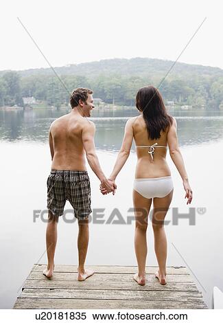 Stock Photography - USA, New York, Putnam Valley, Roaring Brook Lake, Couple standing on pier by lake. Fotosearch