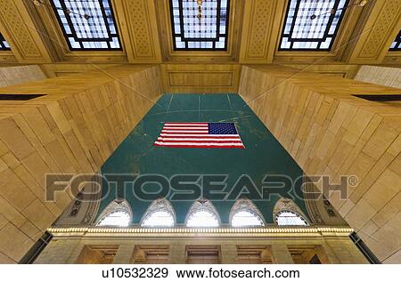 Stock Photo - USA, New York State, New York City, Interior of Grand Central Station with American flag. Fotosearch