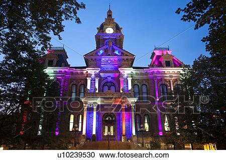 Stock Image - USA, Ohio, Cambridge, Town hall with colorful lights at dusk. Fotosearch