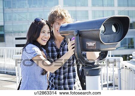 USA, Washington, Seattle, Couple looking through coin-operated binoculars View Large Photo Image Picture - USA, Washington, Seattle, Couple looking through coin-operated binoculars. Fotosearch