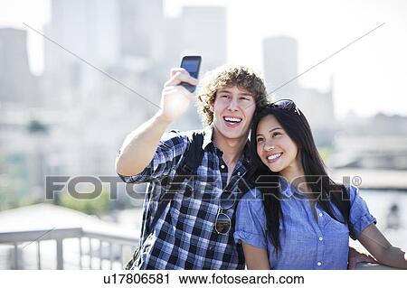 USA, Washington, Seattle, Couple wearing sunglasses photographing themselves with smart phone View Large Photo Image Stock Image - USA, Washington, Seattle, Couple wearing sunglasses photographing themselves with smart phone. Fotosearch