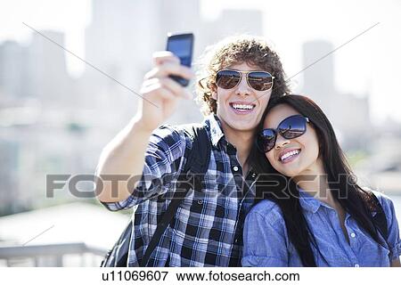 USA, Washington, Seattle, Couple wearing sunglasses photographing themselves with smart phone View Large Photo Image Stock Photo - USA, Washington, Seattle, Couple wearing sunglasses photographing themselves with smart phone. Fotosearch