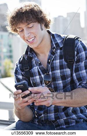 Stock Photo - USA, Washington, Seattle, Man text messaging outdoors. Fotosearch