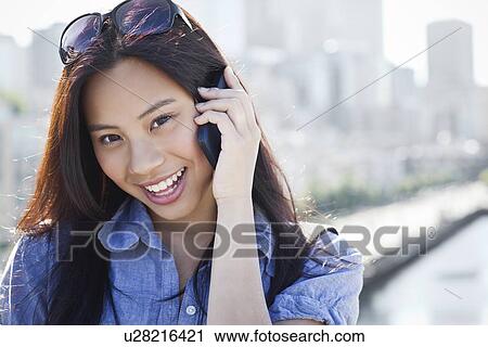 Stock Image - USA, Washington, Seattle, Woman talking on mobile phone outdoors. Fotosearch