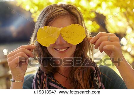 Woman covering eyes with autumn leaves View Large Photo Image Stock Photo - Woman covering eyes with autumn leaves. Fotosearch