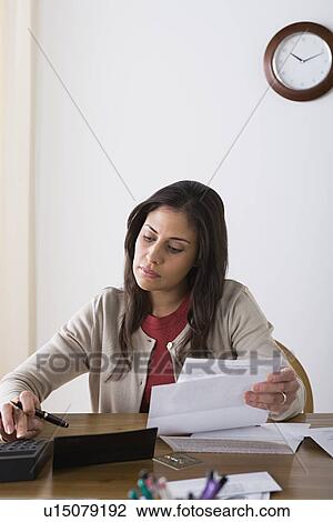 Stock Image - Woman doing paperwork at home. Fotosearch