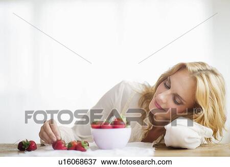Stock Photo - Woman eating strawberries, studio shot. Fotosearch