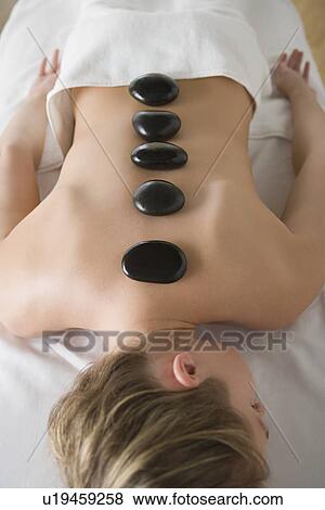 Stock Photo - Woman enjoying hot stone therapy. Fotosearch