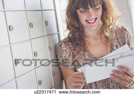 Stock Image - Woman holding letters near mail box. Fotosearch