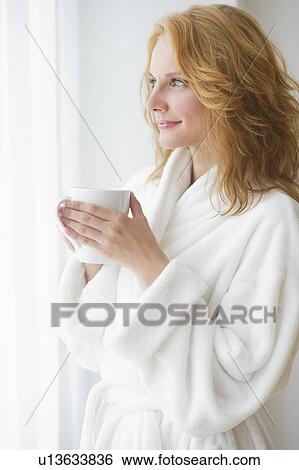 Stock Photograph - Woman in bathrobe drinking coffee. Fotosearch