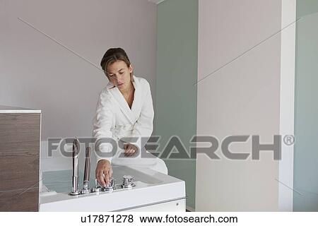 Woman in bathrobe pouring water into tub View Large Photo Image Stock Photo - Woman in bathrobe pouring water into tub. Fotosearch
