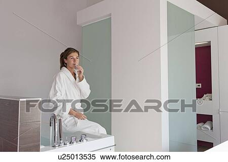 Woman in bathrobe sitting on tub View Large Photo Image Stock Photography - Woman in bathrobe sitting on tub. Fotosearch