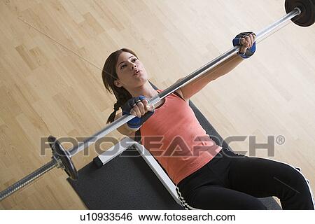 Stock Photograph - Woman lifting barbell in gym. Fotosearch