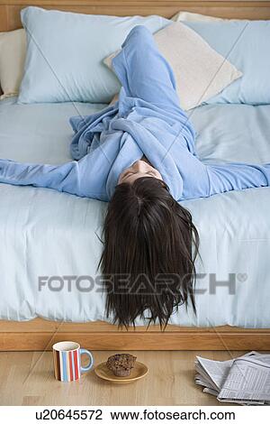 Stock Image - Woman lying on bed. Fotosearch