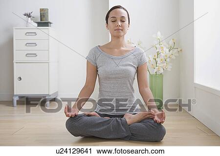 Stock Image - Woman meditating at home. Fotosearch