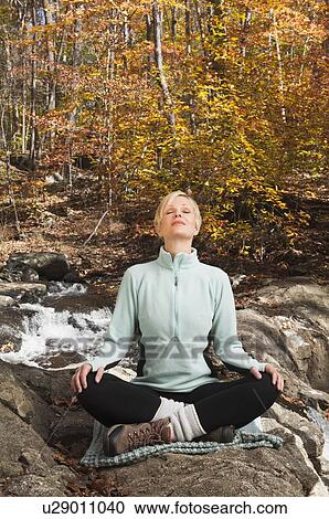 Woman meditating by stream in forest View Large Photo Image Stock Image - Woman meditating by stream in forest. Fotosearch
